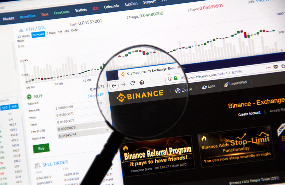 Binance Webseite als Screenshot dargestellt mit Kursen von Kryptowährungen im Hintergrund